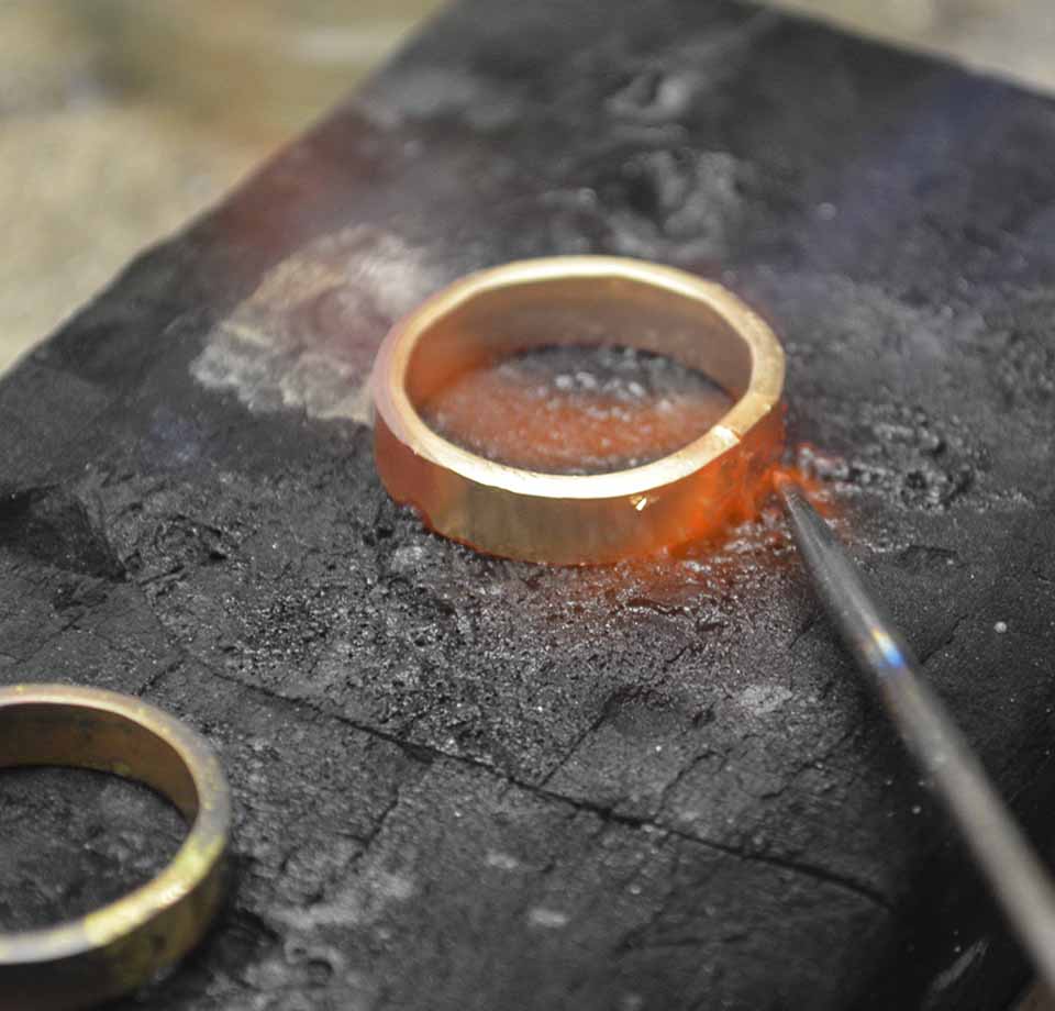 gluehender Goldring auf grauem Stein Goldschmiede Albath